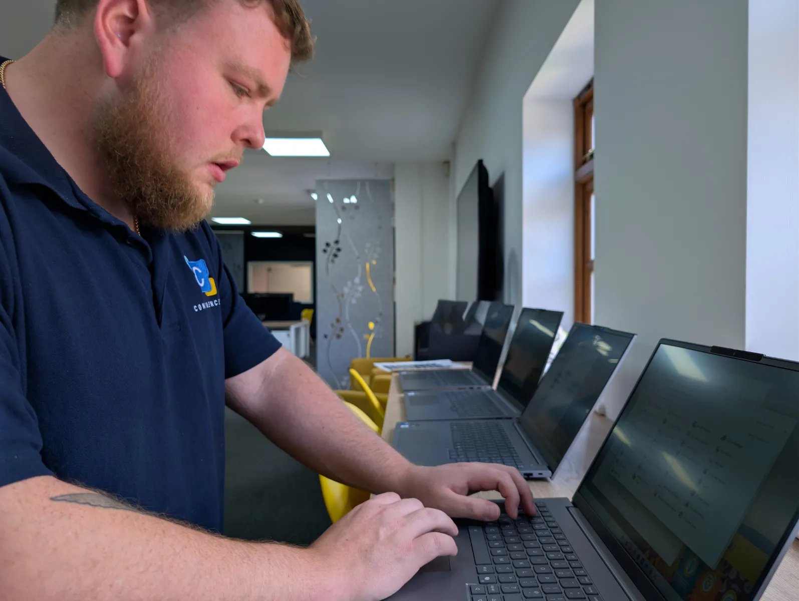 A Confidence IT engineer configuring business laptops in the office