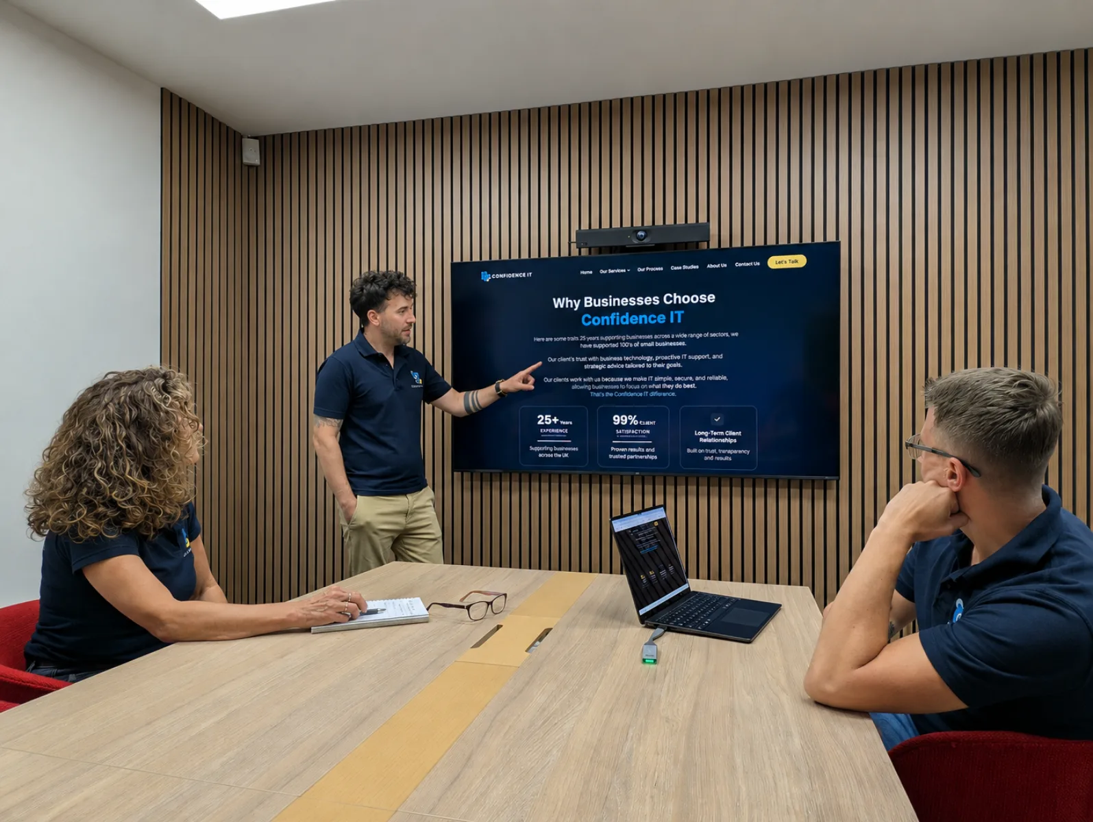 A Confidence IT team member presenting to colleagues in a meeting room