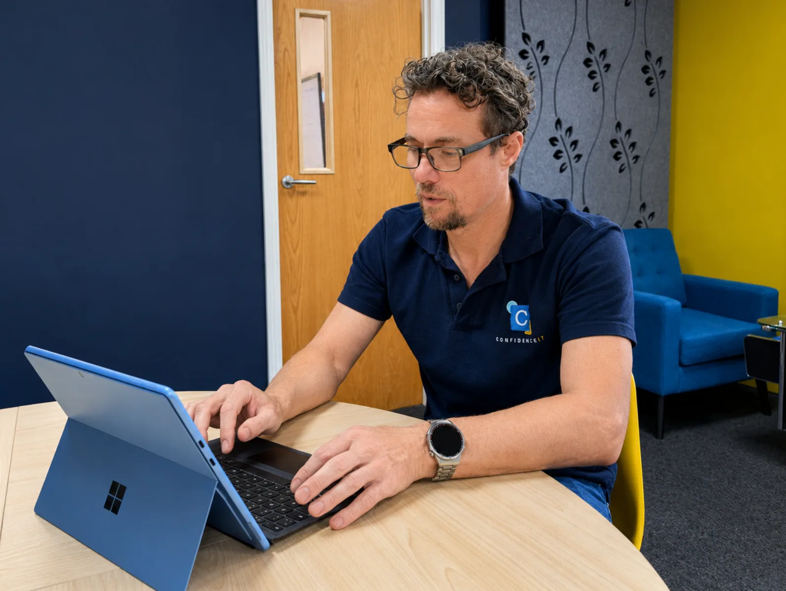 A Confidence IT team member working on a Surface laptop in the office